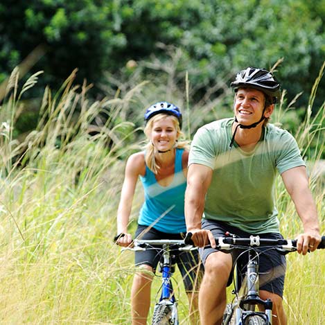 Frau und Mann fahren mit Fahrrad im hochwachsenden Gras